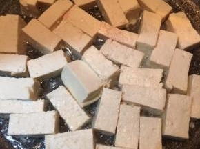 锅中倒入油，大火烧热，下入豆腐转中火煎至呈金黄色。