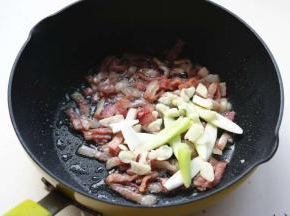 炒锅放少量油，煸香培根后，放入葱蒜爆出香味。