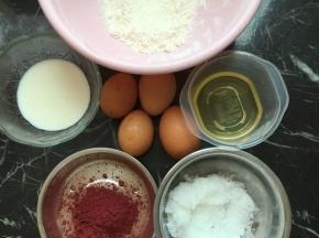 材料准备齐全，准备两个干净无水无油的盆，鸡蛋分离，把蛋黄打入盆里，倒入玉米油和牛奶翻拌均匀，低粉和红曲粉过筛加入盆里，翻拌均匀放一边备用，蛋清放入另一个干净盆里