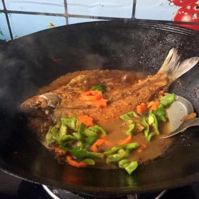 打开看一下水量差不多到了1/2的时候，小心给鱼翻面，放入胡萝卜和青椒，继续盖上锅盖再煮吧