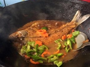 打开看一下水量差不多到了1/2的时候，小心给鱼翻面，放入胡萝卜和青椒，继续盖上锅盖再煮吧