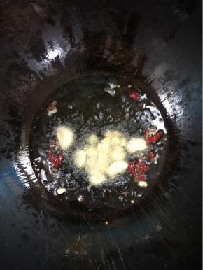 锅烧热倒入适量的猪油融化后，放入蒜瓣，花椒，干辣椒爆香！

