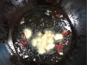 锅烧热倒入适量的猪油融化后，放入蒜瓣，花椒，干辣椒爆香！

