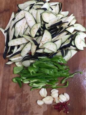 茄子去蒂清洗干净后切成薄片，青椒去蒂去籽切成块儿，蒜瓣剁碎，干辣椒切成段备用！

