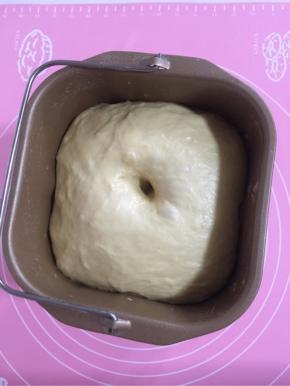 把揉好的面团拿出来，取出面包机转刀，整一个光滑的面放进面包桶中，盖上保鲜膜，常温进行第一次发酵。面团发到约两倍大，用手指沾点面粉在面团中间戳个洞，不塌陷不回缩便是发酵好了。【冬天可以放进烤箱来发酵！】

