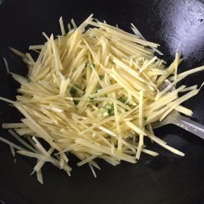 锅里倒适量油，放入葱花爆香，倒入土豆丝