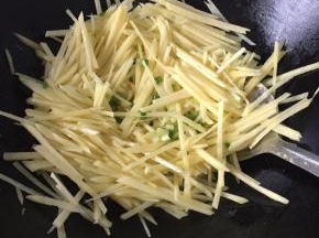 锅里倒适量油，放入葱花爆香，倒入土豆丝