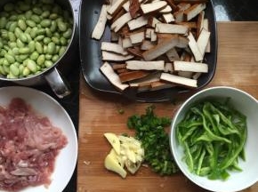 将所有食材洗干净，肉切丝，毛豆去壳去皮，香干切长条，青椒切丝，姜、蒜，葱切碎