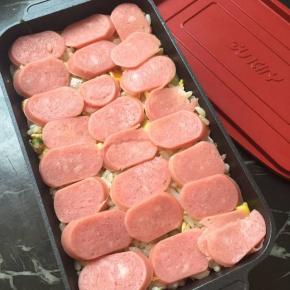 烤肠切片，模具里放入炒好的米饭铺上一层烤肠，再铺上一层芝士