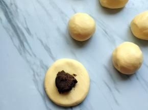 分成大小一样的小剂子，按扁放入豆沙馅收口滚圆