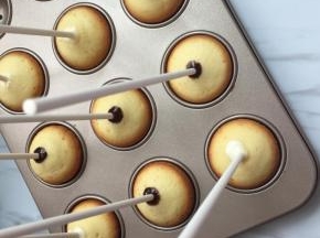 蛋糕出炉以后，冷却以后脱模，用棒棒糖纸棒蘸少许融化的巧克力。将纸棒插在烤好的圆形小蛋糕上。然后将小蛋糕放回模具里，等待巧克力凝固