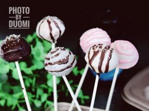 纸棒固定好以后，在融化的巧克力液里滚一圈，使表面蘸满巧克力液，慢慢提起蛋糕。凝固后将剩余的巧克力液倒入裱花袋里挤在棒棒糖蛋糕上稍作装鉓就好了