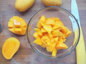 芒果沿着果核切开，用刀在果肉上划十字刀，再把果皮翻转，沿着果皮用刀将果肉轻轻切下