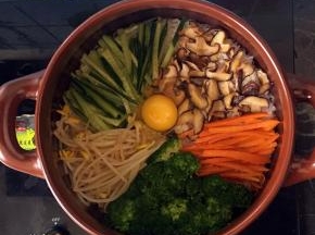 米饭煮至水分快干的时候，调小火，放入香菇，胡萝卜，豆芽，西兰花和黄瓜，中间打一个鸡蛋，盖上盖子焖煮至听到哧哧的声音关火