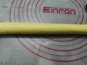 案板上洒一层簿簿的面粉，手上也蘸一点手粉，将冷藏后的面团揉成团后，再搓成长条形