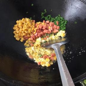 锅热倒适量油，打入鸡蛋搅碎，倒入葱花出香味倒入火腿丁，玉米粒炒匀