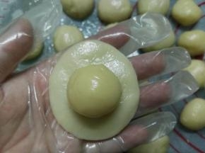 取一个油皮用手压扁，将油酥包进油皮里面。