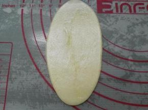 取一个油酥皮用擀面杖从中间开始向两头擀开，擀成牛舌状