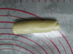 将擀好的油酥皮从上往下卷起。