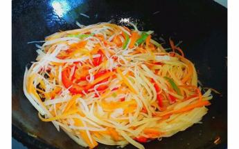 然后倒入土豆丝和青红椒翻炒，加入一勺醋，待土豆丝炒软，加入盐和鸡精调味即可