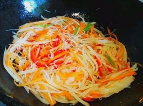 然后倒入土豆丝和青红椒翻炒，加入一勺醋，待土豆丝炒软，加入盐和鸡精调味即可