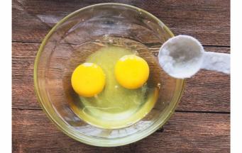 碗内打入两个鸡蛋，加入白糖和食盐搅拌均匀