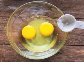 碗内打入两个鸡蛋，加入白糖和食盐搅拌均匀