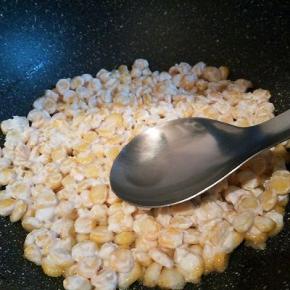  开中火，放入玉米粒，用勺子轻轻的把它们摊成圆形，（勺子可以再刚才倒出的油盘里沾一下油，这样在按玉米粒的时候不会粘）大概煎2到3分钟，