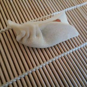 一只手拿着饺子，一只手把后面的饺子皮捏个褶，