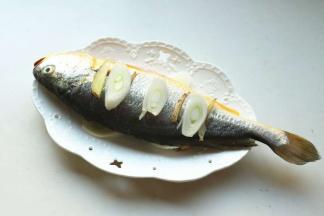 鱼身表面打花刀，抹少许盐腌一会。放入盘子，放入姜片葱段，鱼下面和鱼肚子里也放上。