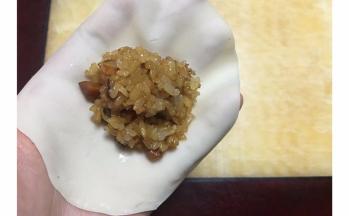 取一张饺子皮，用擀面杖再擀薄擀大一些~中间放适量糯米
