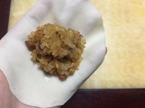 取一张饺子皮，用擀面杖再擀薄擀大一些~中间放适量糯米