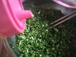 切碎的韭菜放入盆里，倒入玉米油用筷子搅匀，让韭菜碎上都裹上玉米油。