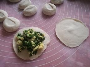 用手掌按扁，然后用面杖擀成圆形面片，包入韭菜馅。