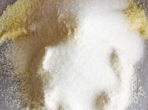 取一张油纸，将杏仁粉，低粉过筛，加入砂糖，用手把它们混合到一起