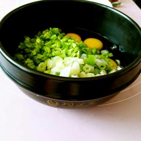取一个容器（我用的是我的小可爱-陶煲王的小石锅），把鸡蛋打入，再放入苦瓜碎，葱花和适量的盐。