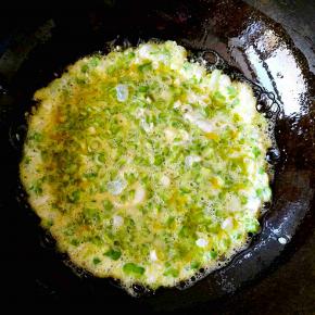 锅中放油，倒入搅拌好的苦瓜鸡蛋液。晃动锅体，使蛋液均匀铺开，中火定型之后翻面，这里要说的是如果你像我一样有足够厉害的颠炒勺本领，那就用普通的炒锅，给蛋饼翻身就是一秒钟的事儿。如果你不具备这个本领，最好还是用平底锅，一面定型了之后，把蛋饼滑入一块平盘中，然后左手拿锅，右手托住盘子，把锅覆盖在盘子上，再一翻转，好，蛋饼又到锅里面去了，翻身的目的达到了。