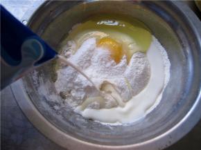 然后分次慢慢的加入牛奶，以打蛋器搅拌至完全融合。每次加入后都要搅拌均匀再加下一次，最后成糊状。