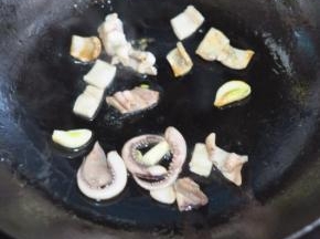 锅里倒油，放入蒜和鱿鱼。