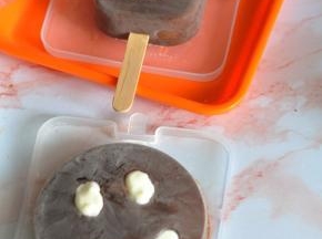 将少量的淡奶油打发，装入裱花袋中，雪糕脱模后，填充在眼睛和嘴巴的地方。