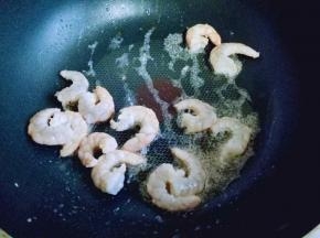 热锅冷油，加入腌制好的虾仁煸炒。炒至颜色变红。