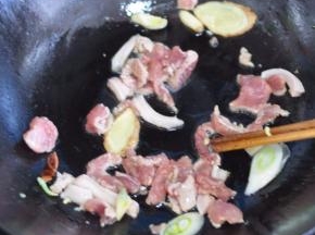 锅里倒入油，放入花椒、大料，放入腌好的肉翻炒，加入葱、姜、蒜。