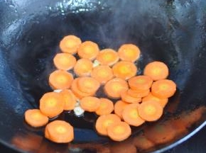 锅里倒入油，放入蒜炸香，放入胡萝卜片翻炒。