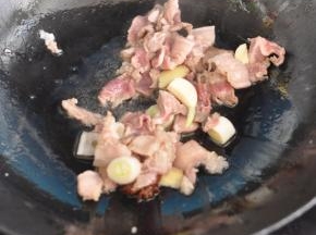 锅里倒入油，放入花椒、大料，放入猪肉翻炒，同时加入葱、姜、蒜。