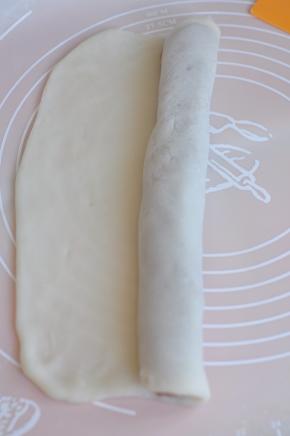 从有馅的一端卷起，尾端边缘的皮要擀薄一点。
