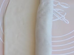 从有馅的一端卷起，尾端边缘的皮要擀薄一点。
