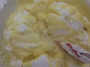 把三分之一蛋白放入蛋黄糊，用切菜手法不断切均匀，再放三分之一继续切均匀