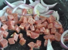 将牛排切丁，放入锅中翻炒。