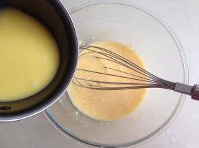 将溶化了黄油的牛奶倒入面粉糊里，一边倒，一边搅拌