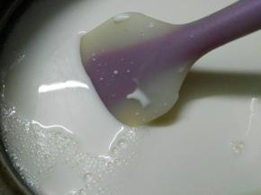 把纯牛奶倒入装有FLUFF棉花糖的小锅，将小锅放煤气灶上小火加热，用刮刀不断搅拌，将FLUFF棉花糖融化并与纯牛奶混合均匀